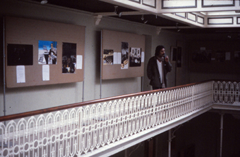 colour photo showing the inside gallery at the africa centre and a thoughtful looking man looking at the art attacks apartheid pictures