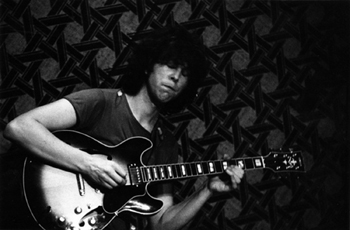 black and white photo of Phil Miller playing guitar live on stage