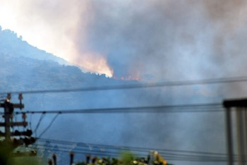 orange red flames licking alight the trees at the foot of montrous mountain