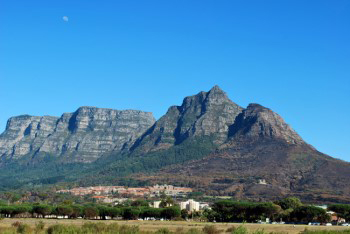wide angle photo view of devils peak under bright blue sky with three quarter moon