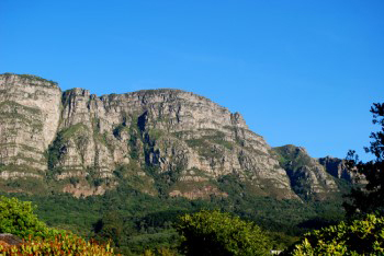 East side of Table Mountain  on warm sunny day with different shades of green vegetation in the valley below the mountain and on its sides.