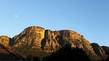 Moon setting in blue sky at sunrise over the east side of table mountain.