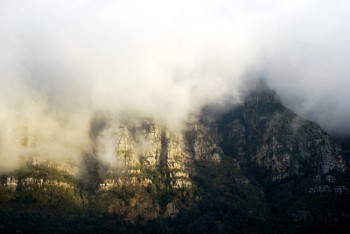 High tops of Fernwood, Protea and Hiddingh buttresses almost completly covered in low white clouds with patches of sunlight filtering through the clouds onto the Fernwood and Protea buttresses.