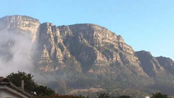 A sea mist drifts slowly over the face of a sunny Table mountain east side Cape Town